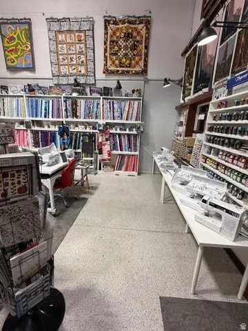 Commercial space featuring exposed ceiling infrastructure, track lighting, light-colored speckled flooring, and extensive built-in shelving