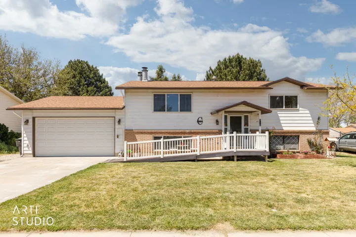 Split-level residence featuring white siding and a prominent attached two-car garage