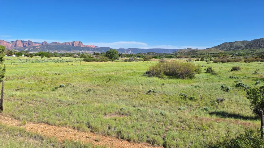 Expansive rural landscape featuring a vast, grassy field under a clear blue sky