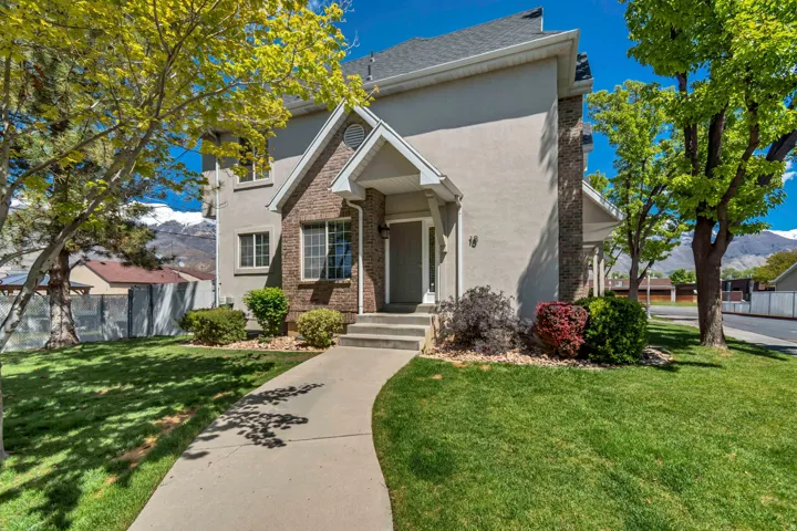Traditional stucco and brick exterior featuring a stone accent chimney and gabled entry