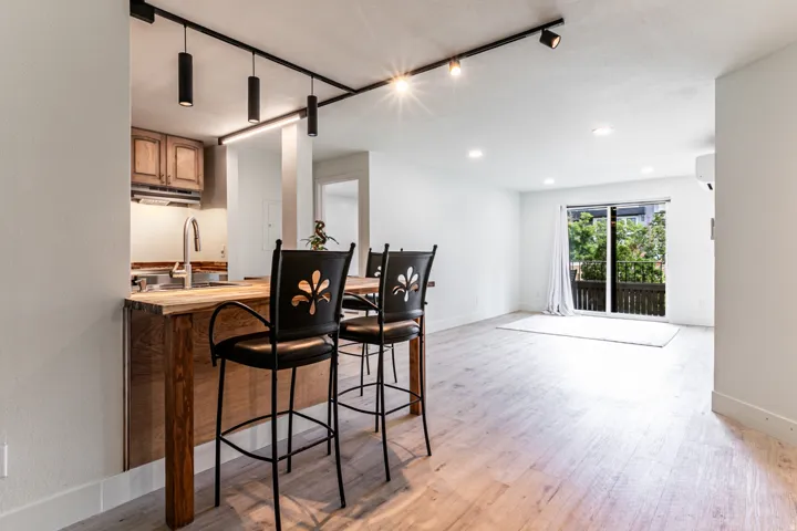 Open-concept living area featuring light wood-finish flooring and a kitchen pass-through with a natural wood countertop