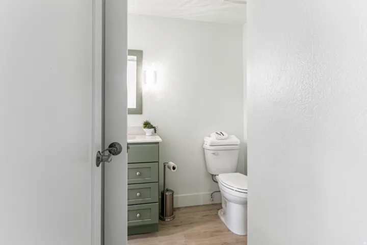 Bathroom with a sage green vanity featuring three drawers and a white countertop