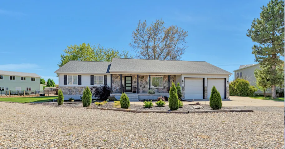 Ranch-style exterior with stone veneer and white siding, featuring a dark asphalt shingle roof