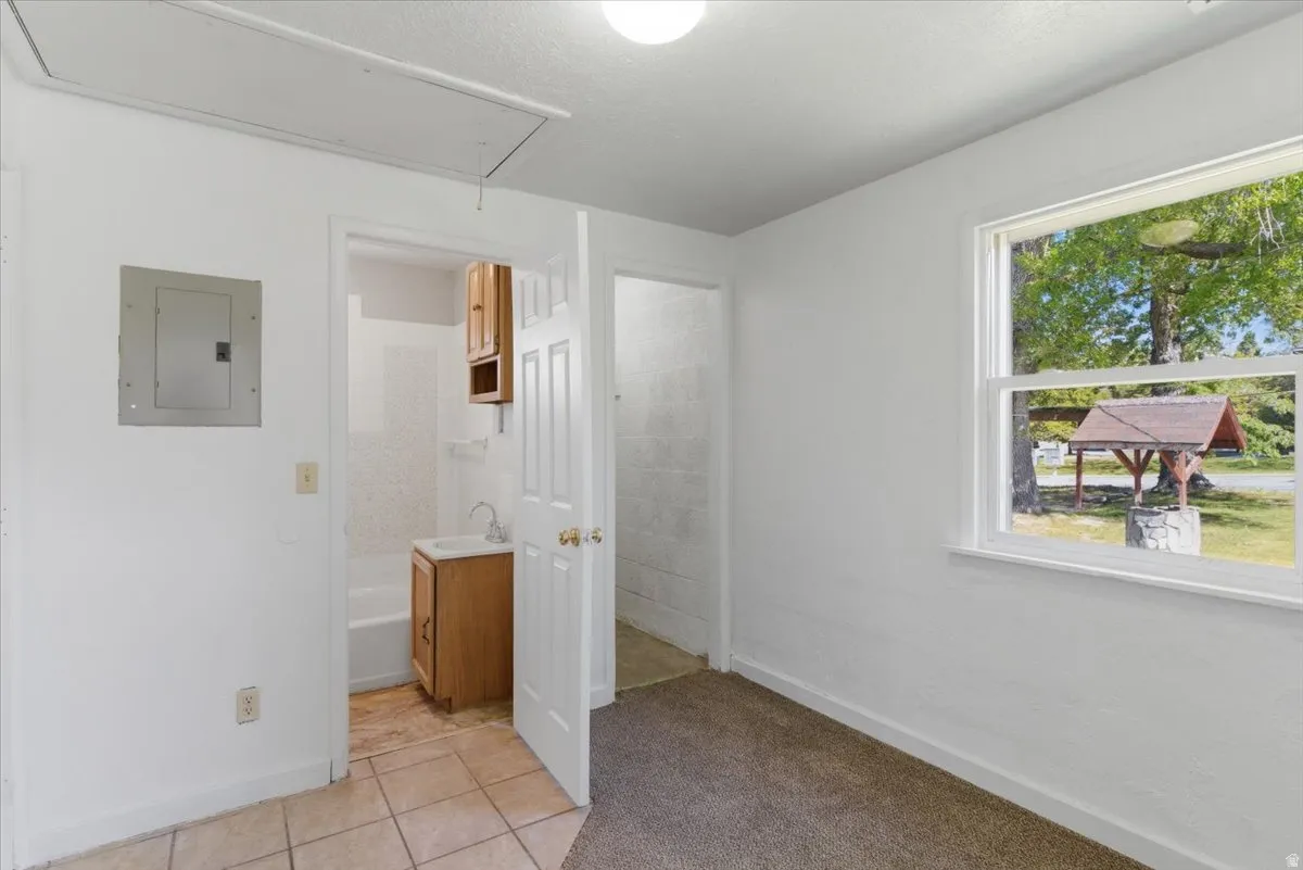Bright interior space featuring a window overlooking a wishing well and mature trees