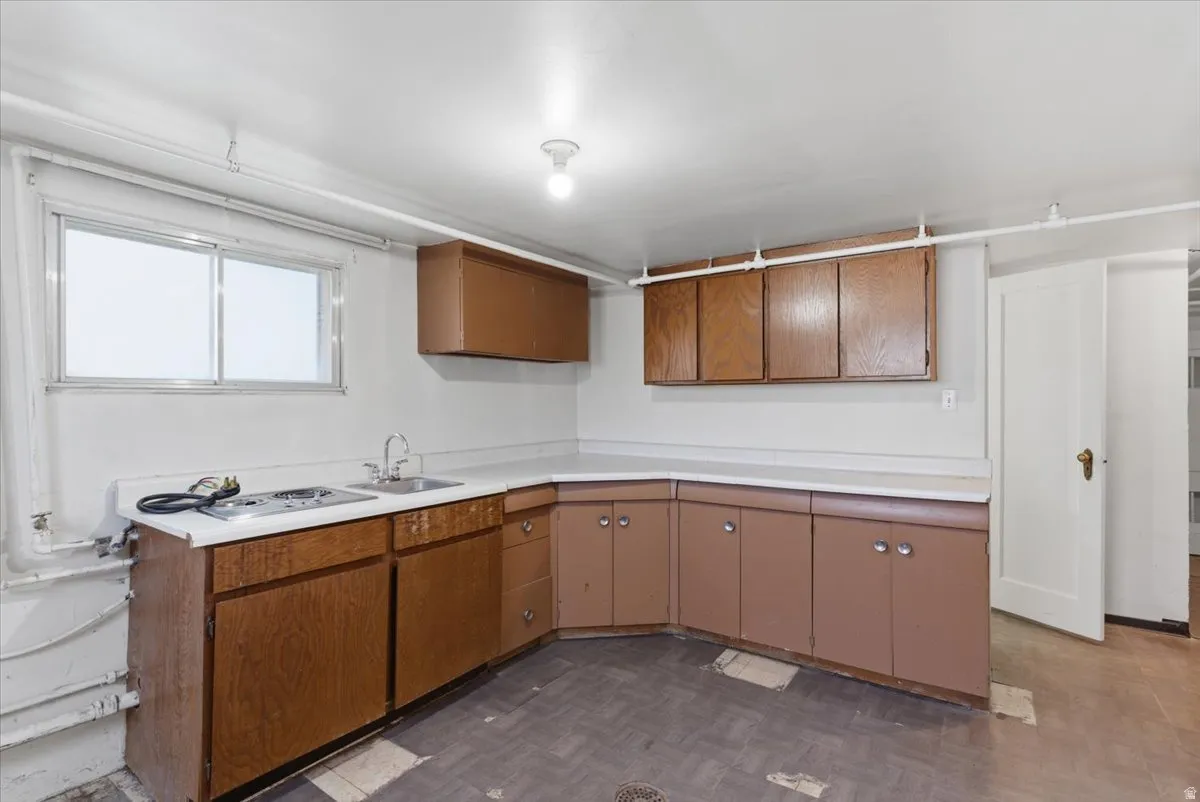 Kitchen area featuring wood-finish cabinetry, white countertops, a stainless steel sink, and a two-burner cooktop