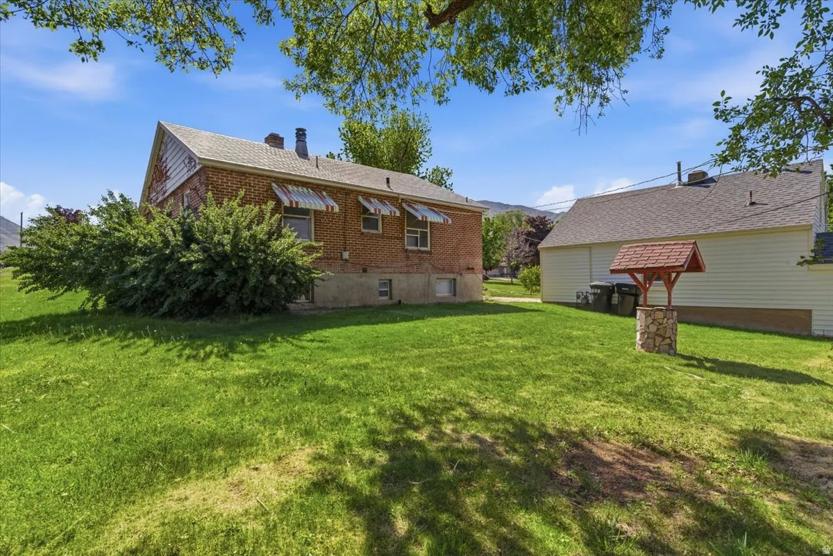 Expansive backyard featuring a green lawn, mature trees, and a decorative wishing well