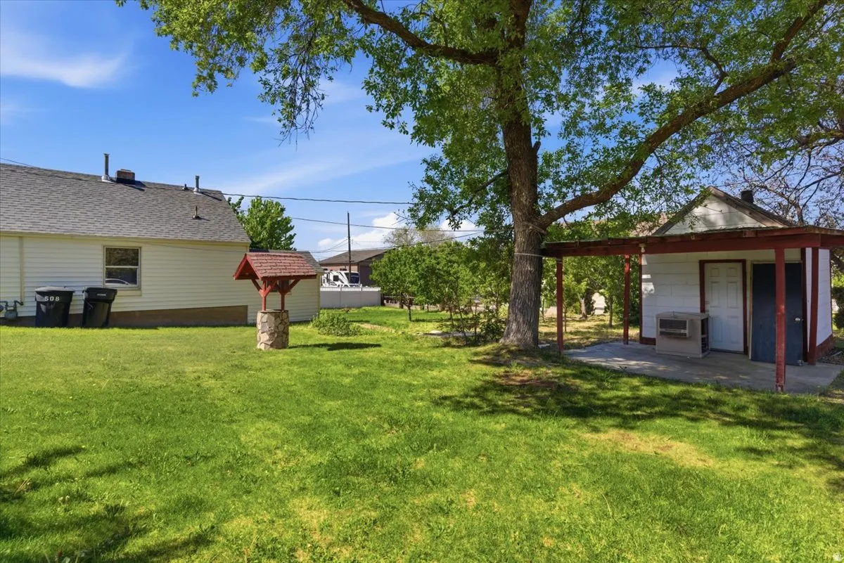 Expansive green lawn with a mature shade tree and a stone-clad wishing well