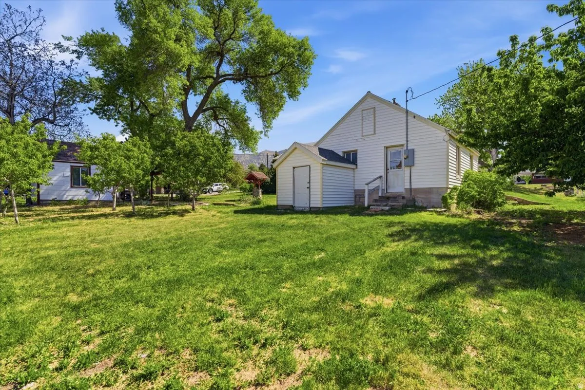 Expansive yard featuring a detached storage shed, mature trees, and a white siding exterior