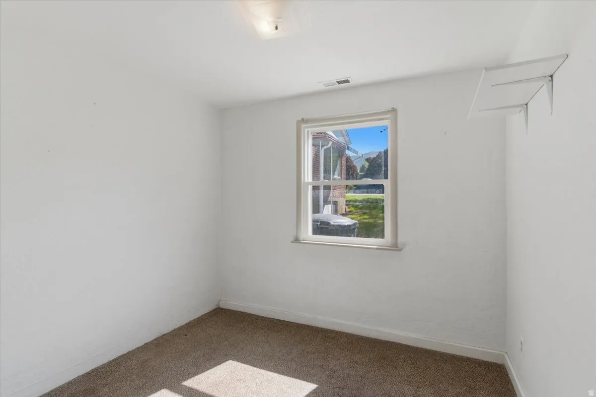 Carpeted room featuring a single window and white walls