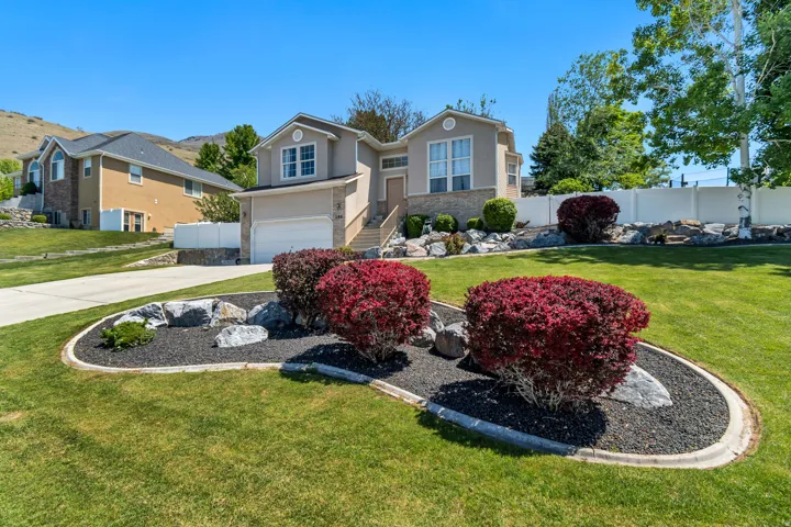 Multi-level home featuring a stucco and stone veneer exterior, a two-car garage, and an elevated entrance