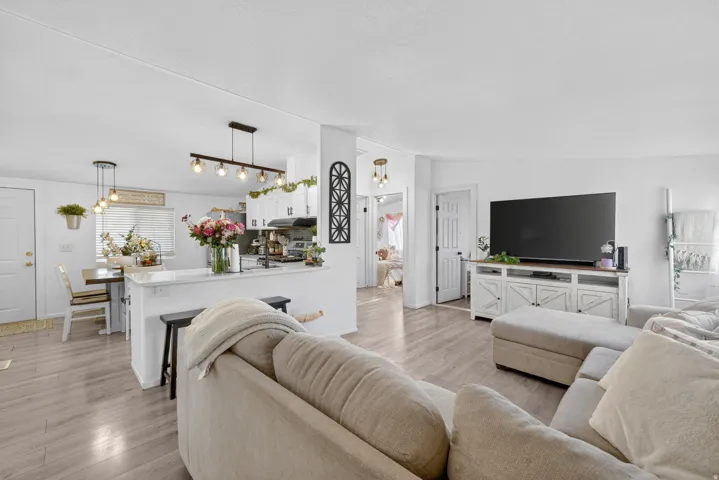 Open-concept living area featuring light wood-finish flooring, white walls, and recessed lighting