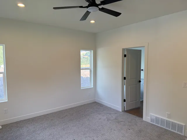 Recessed ceiling lighting, ceiling fan with light, two panel interior door with matte black hardware, and two windows
