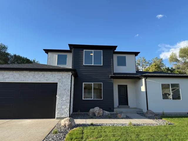 Contemporary exterior with multi-toned siding, stone veneer accents, an attached garage, and a concrete pathway
