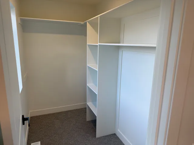 Walk-in closet featuring built-in shelving, hanging rod, and carpeted flooring