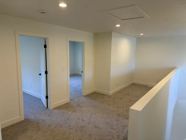 Carpeted loft area with recessed lighting, white interior doors, and a neutral color palette