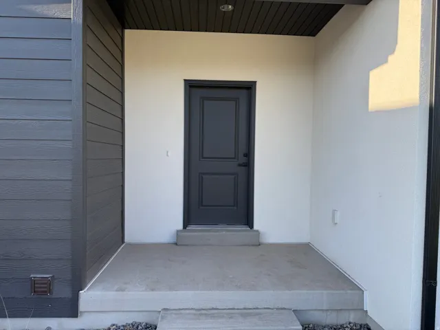 Modern exterior featuring horizontal plank siding, smooth stucco finishes, a dark paneled entry door, and a covered concrete porch