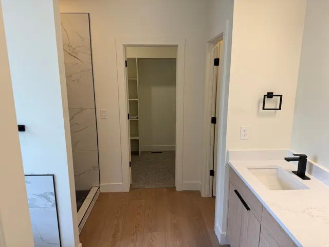 Modern vanity with light wood-finish cabinetry, quartz countertop, and matte black faucet