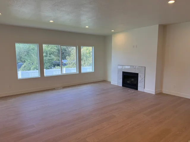 Spacious interior with wood-finish flooring, recessed lighting, and a fireplace with a tiled surround