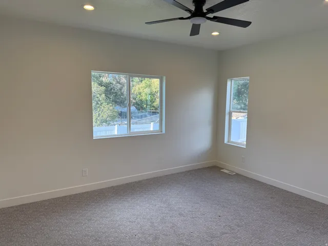 Recessed lighting, ceiling fan, neutral wall tones, carpeted flooring, and white window trim
