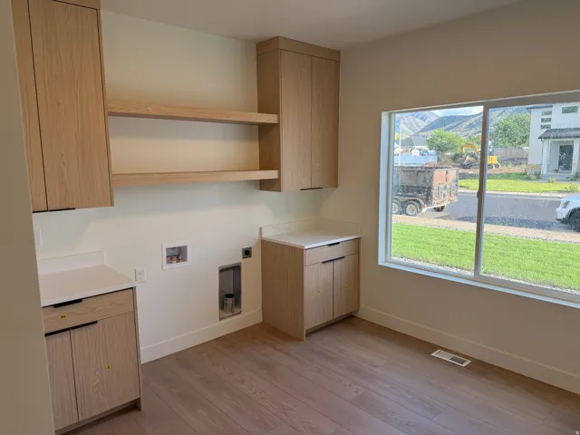 Modern kitchen featuring custom wood-finish cabinetry, open shelving, stainless steel appliances, and warm wood-finish flooring throughout