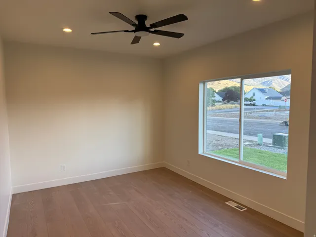 Recessed ceiling lighting with a ceiling fan, wood-finish flooring, and a large window with mountain scenery