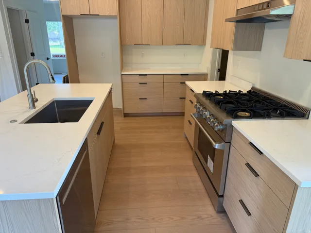 Kitchen with white countertops, wood-finish cabinetry, stainless steel sink, stainless steel range, and wood-finish flooring
