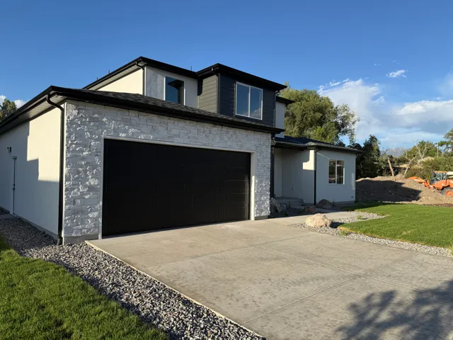 Contemporary exterior with stone veneer accents, stucco siding, a two-car garage, and a concrete driveway
