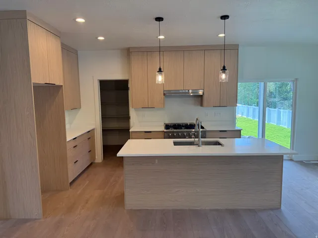 Modern kitchen featuring wood-finish cabinetry, white countertops, and wood-finish flooring