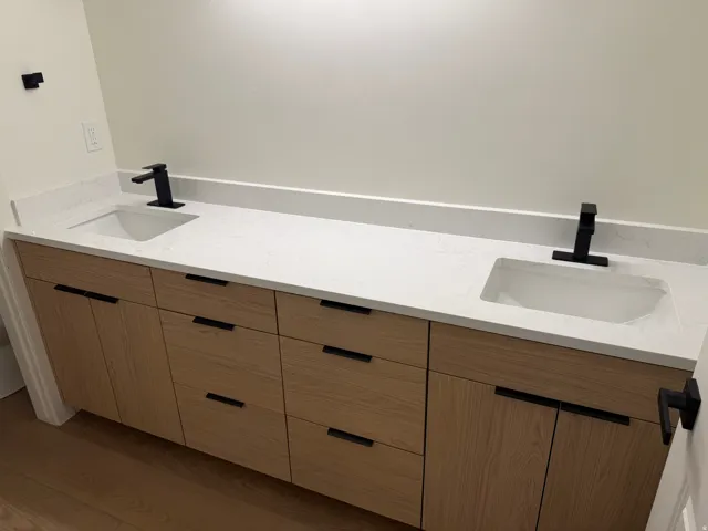 Dual vanity with undermount sinks, stone-finish countertop, matte black faucets, and wood-finish cabinetry
