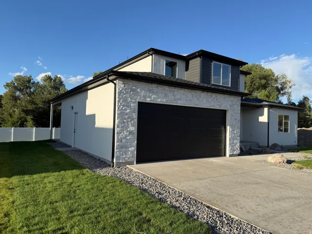 Modern exterior with a stone veneer accent, stucco siding, and a two-car garage