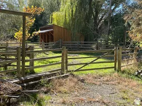 Fenced property featuring a natural wood split rail fence and a rustic wooden shed with an overhang