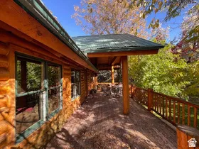 Expansive wood deck with a full-length wood railing and a covered portion featuring exposed wood beams