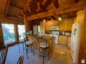 Open-concept kitchen featuring extensive wood cabinetry, a built-in breakfast bar with stone-finish countertop, and integrated appliances