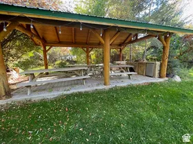 Outdoor wood pergola featuring a green metal roof and integrated string lighting