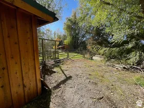 Hardwood-sided structure featuring a green roofline, set within a fenced perimeter