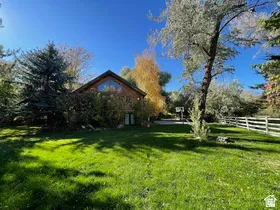 Expansive green lawn with mature trees and a white split-rail fence