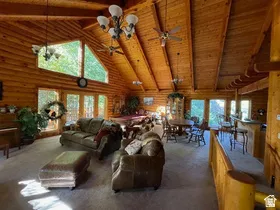 Spacious great room featuring extensive log-style walls, a vaulted wood-finish ceiling, and exposed beams