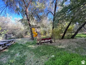 Expansive outdoor space featuring a swing set, slide, and rustic picnic table
