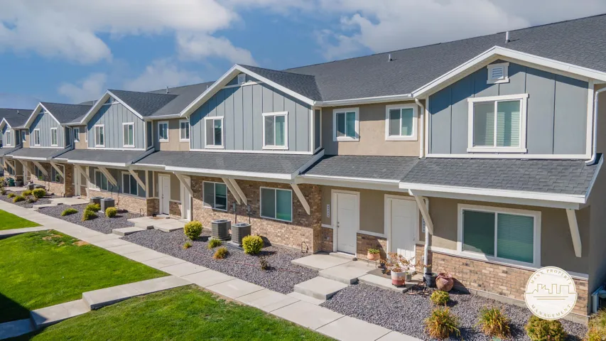 Row of modern townhomes featuring a combination of brick and siding exteriors, individual front entrances, and pitched shingle roofs