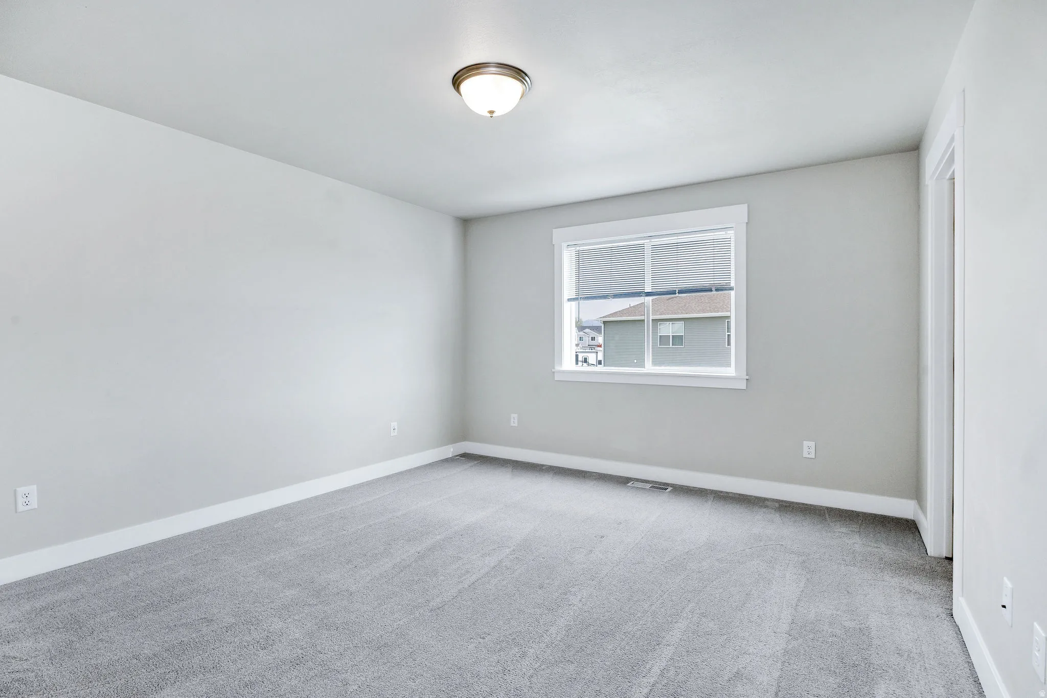 Well-lit interior space featuring neutral wall tones, white trim, and light gray carpeting
