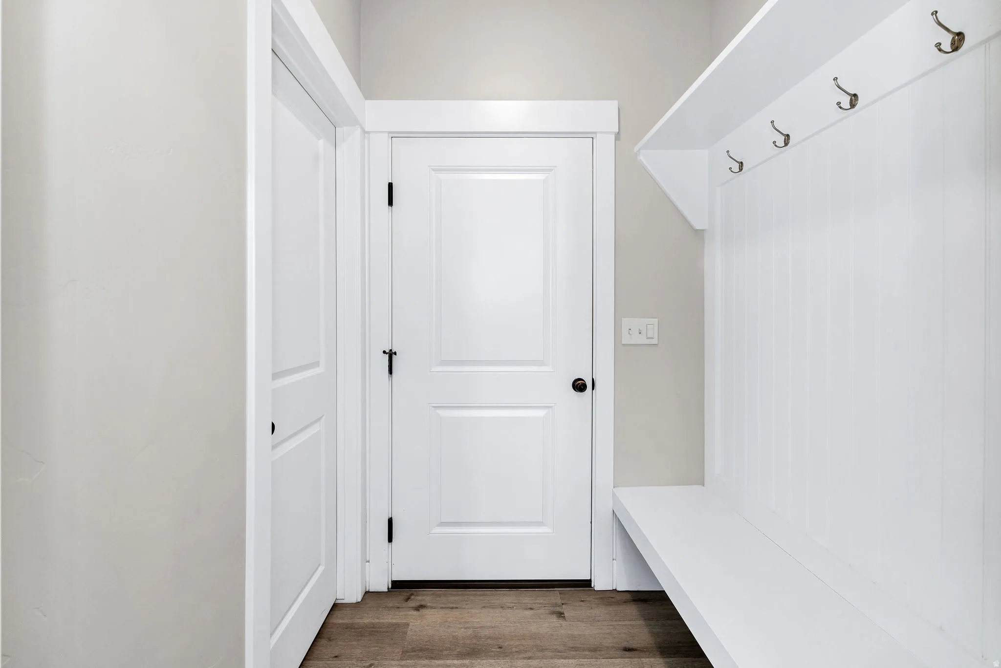 Built-in mudroom bench with beadboard backing, overhead shelf, and bronze-finish hooks