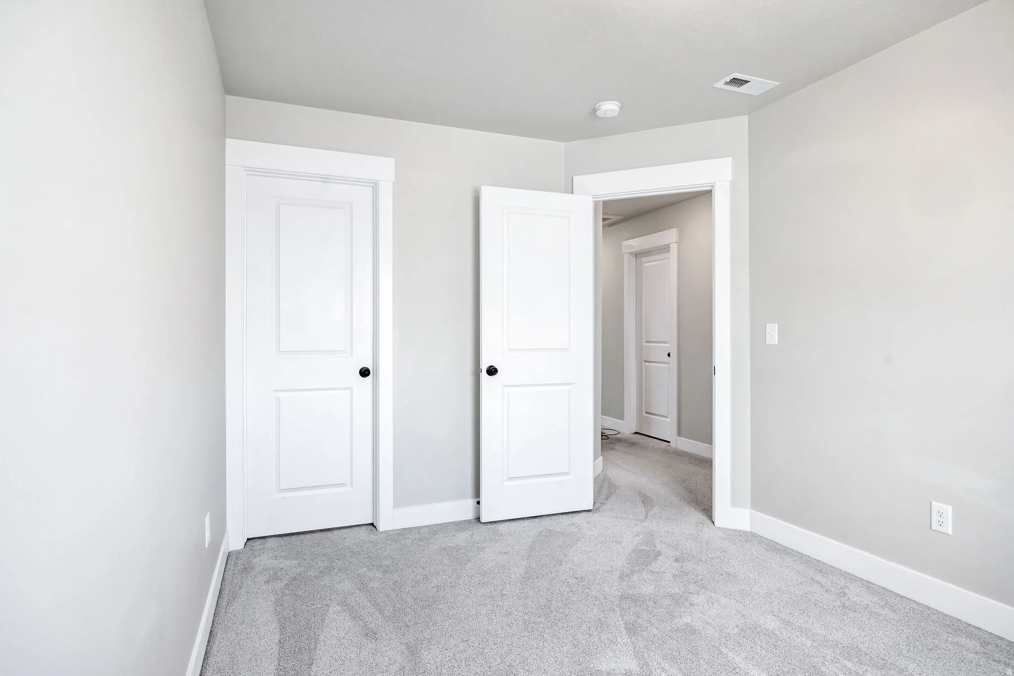 Light gray walls with white trim and gray carpeting