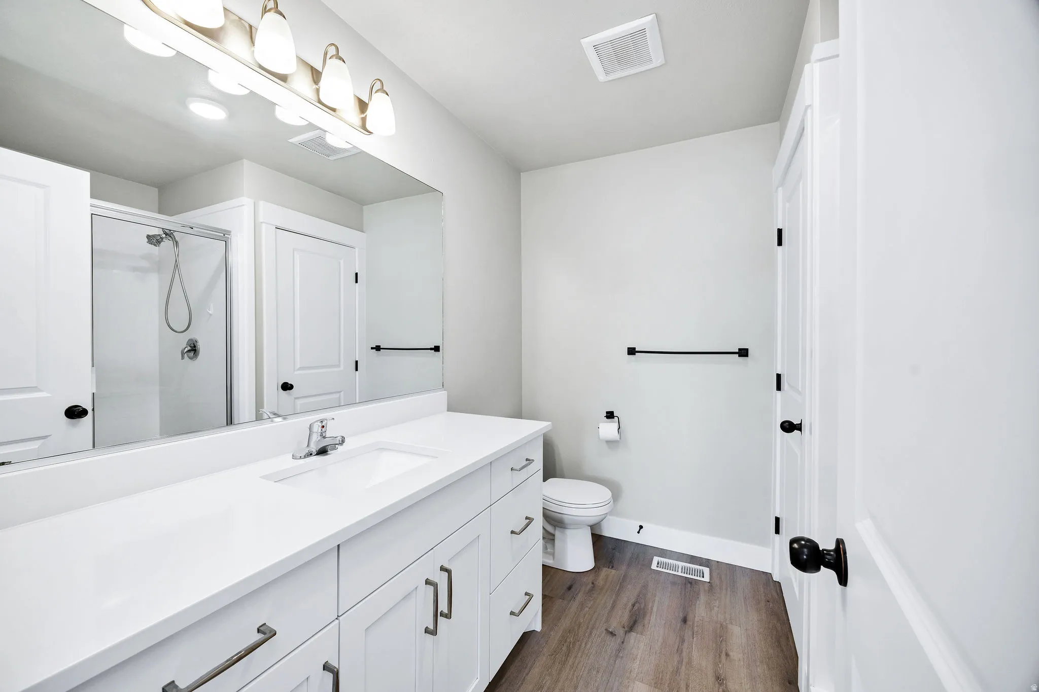 Spacious bathroom featuring a white vanity with integrated sink, chrome faucet, and ample storage cabinetry