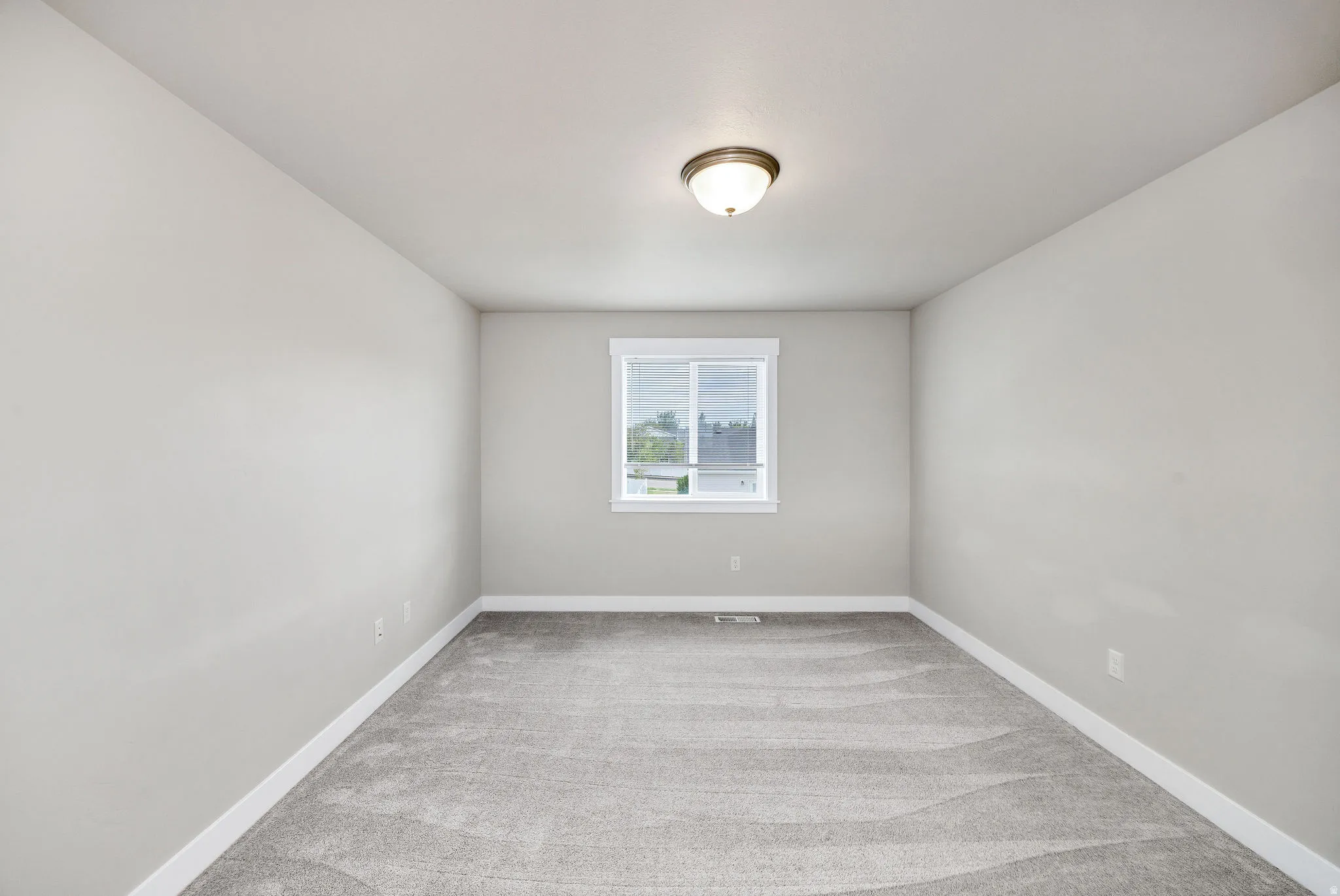 Neutral gray wall paint with white trim, gray carpet flooring, and a flush-mount ceiling light fixture