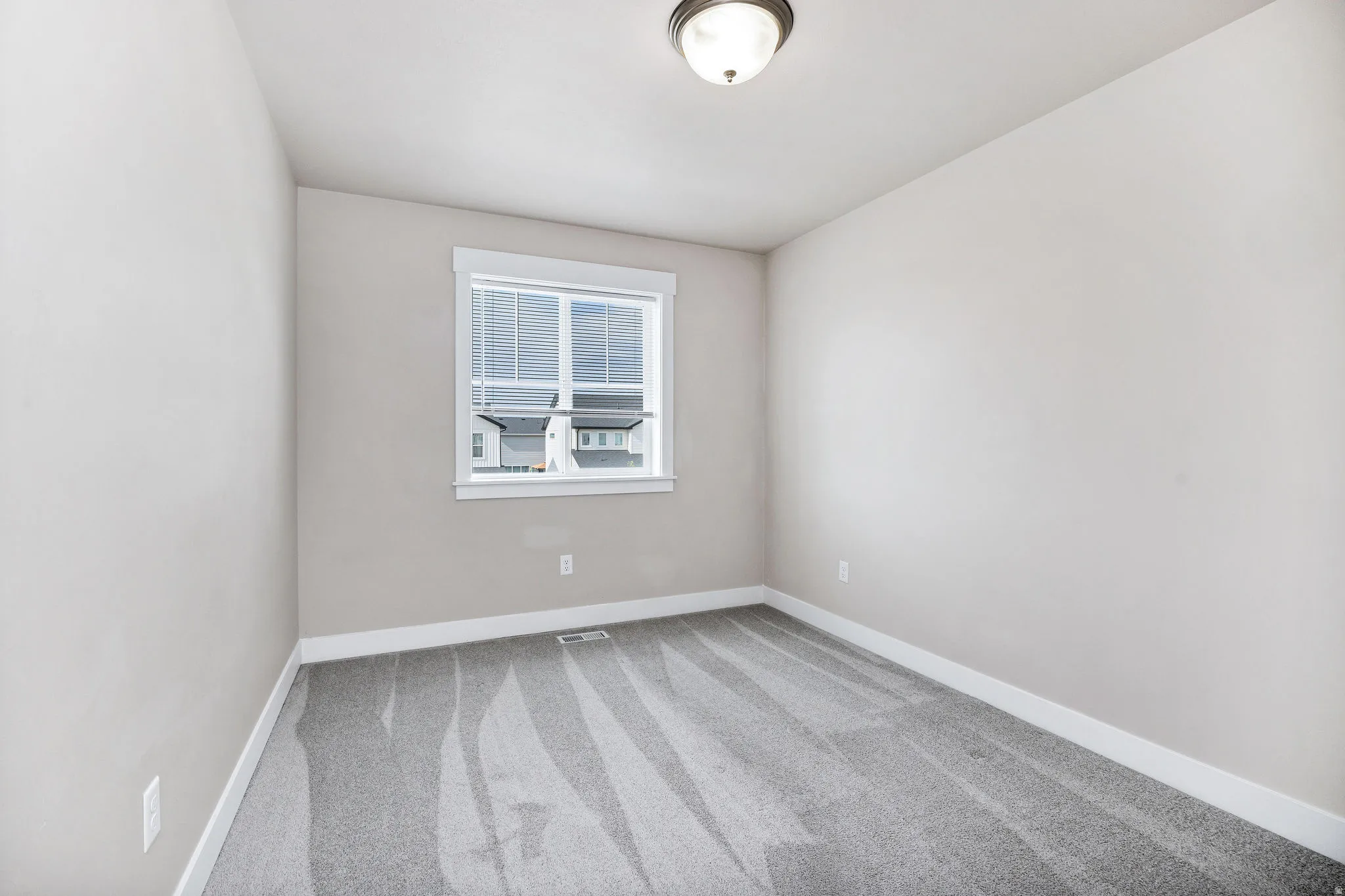 Light gray wall paint with white trim, gray carpet, and a white-framed window