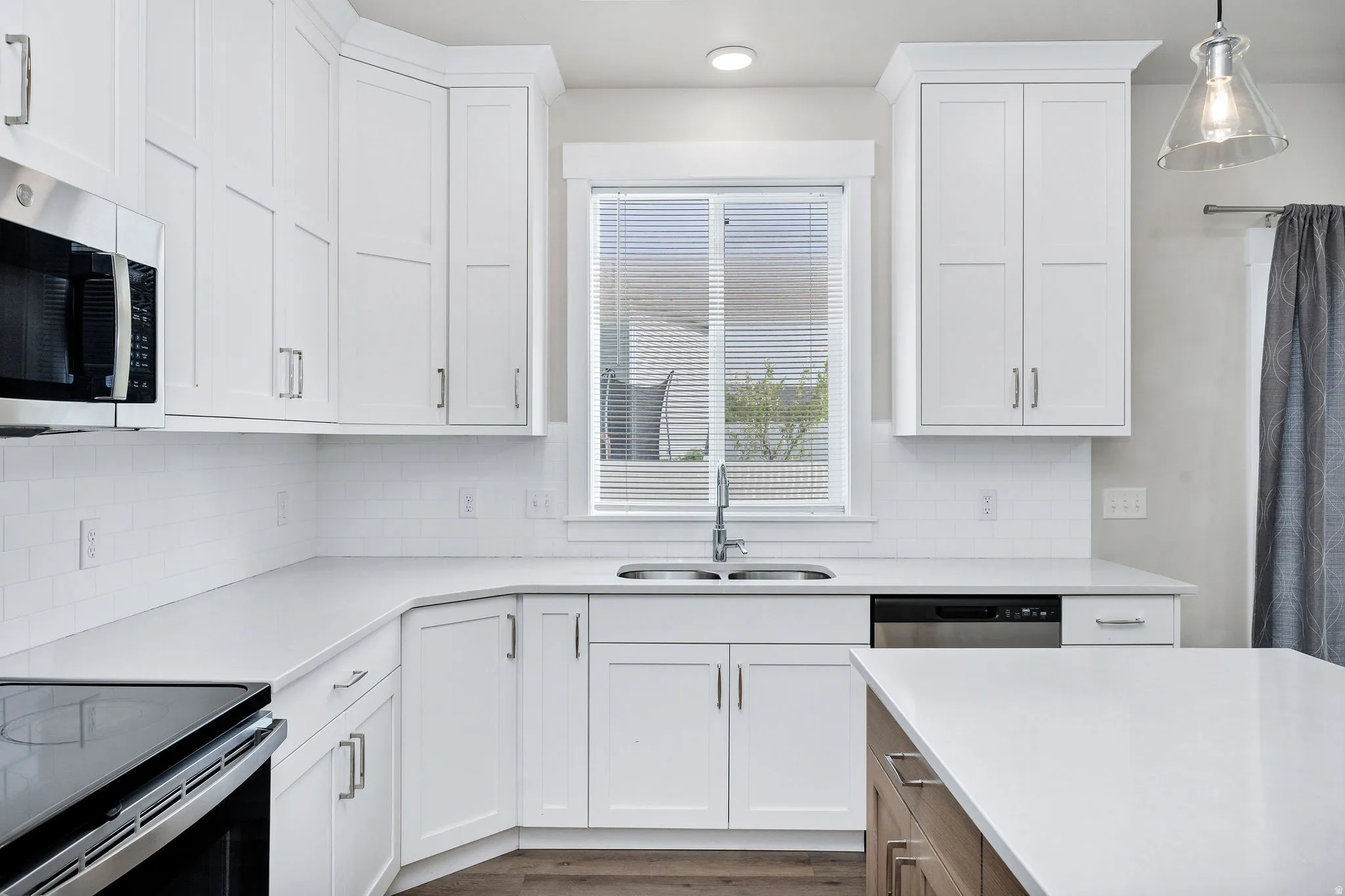 Kitchen featuring white shaker cabinetry, white subway tile backsplash, stainless steel appliances, and solid surface countertops