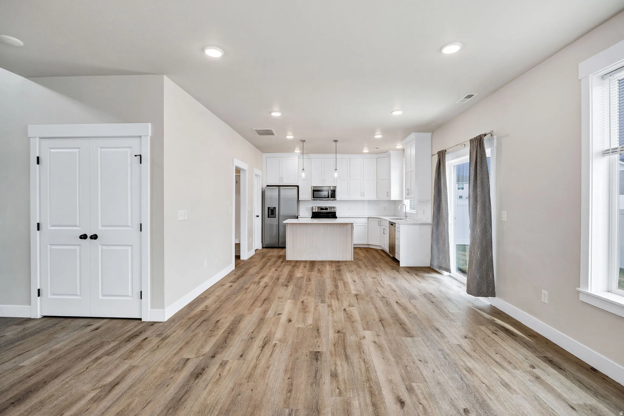 Open-concept living space featuring wood-finish flooring, recessed lighting, and a modern kitchen