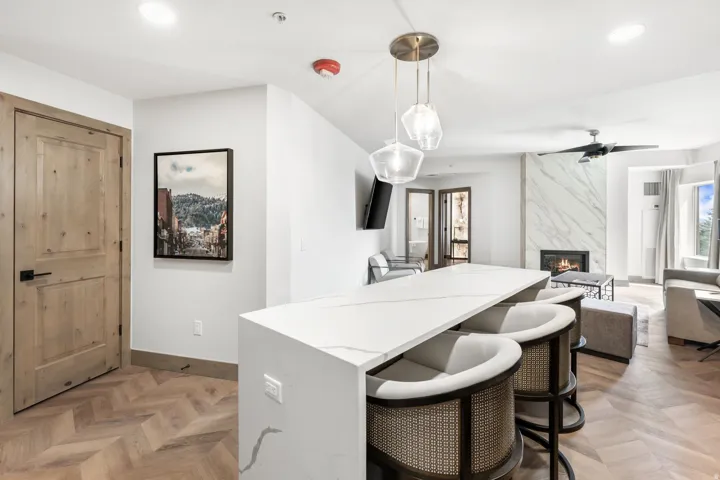 Kitchen island with a waterfall countertop and integrated seating, illuminated by a multi-pendant fixture