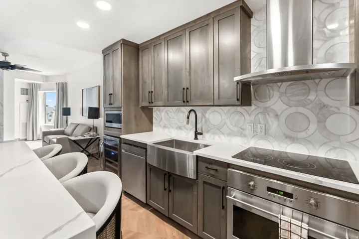 Contemporary kitchen featuring wood-finish cabinetry, stainless steel appliances, a large farmhouse sink, and a unique circular pattern backsplash