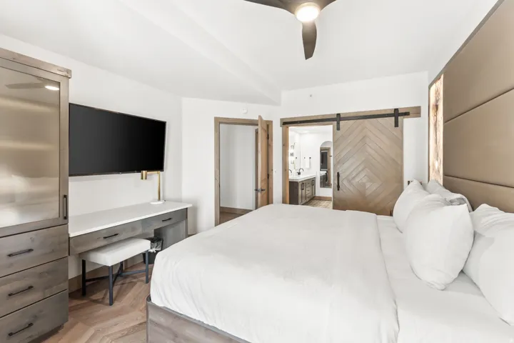Spacious interior featuring a decorative barn door, wood-finish flooring, and a ceiling fan